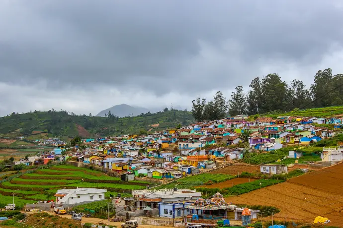 houses near green trees under white clouds during daytime